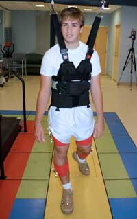 A patient walks along a marked pathway in the clinic while infrared cameras capture his movements by “seeing” the reflective markers that are attached to his legs.