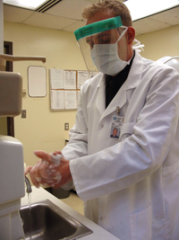 Christopher Beadle washes his hands and gears-up with a mask and face shield to meet with a patient. Providing a sterile environment for each patient is important to reduce the risk of infection.