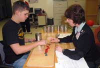 Lt. Col. Karoline Harvey uses basic items like cans and checkers to evaluate a patient's hand function during the Jebsen-Taylor Functions test.