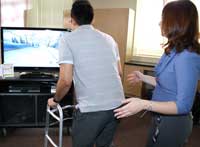 A patient uses a Wii skiing game to work on balance, as Mary Carson oversees.