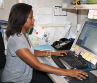 Nicole works on the computer at her desk to compile and analyze research data.