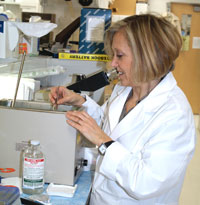 Ofelia retrieves test tubes incubating in a water bath.