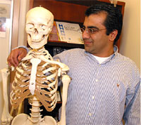 Sunil standing with a model of a human skeleton